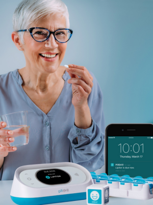 Older woman taking medication with PillDrill hub and system in foreground